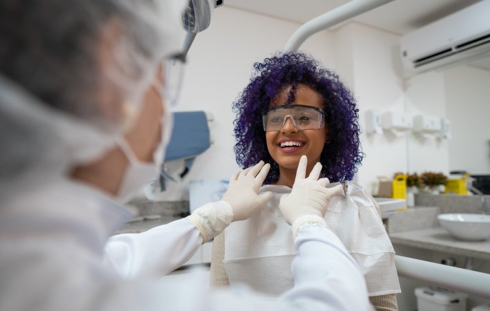 patient wearing protective glasses gets mouth examined